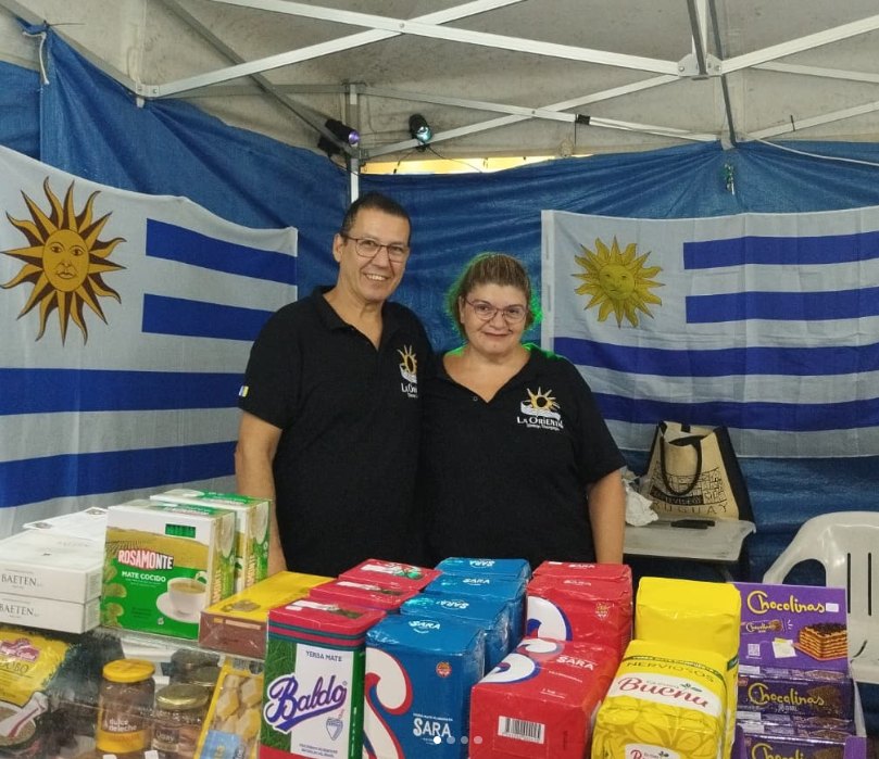 Los dueños de Bazar La Celeste en su puesto, con banderas de Uruguay